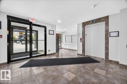 Building lobby featuring tiled flooring, a glass entry system with black framing, and a white elevator with a tiled surround - 