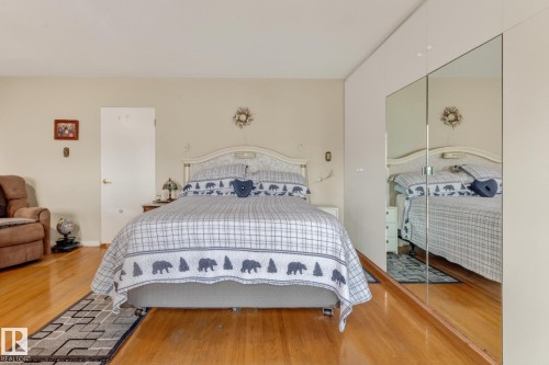 Hardwood flooring, painted walls, white interior door, and mirrored closet doors - 13432 134 Street Nw, Edmonton, AB - Indoor Photo Showing Bedroom
