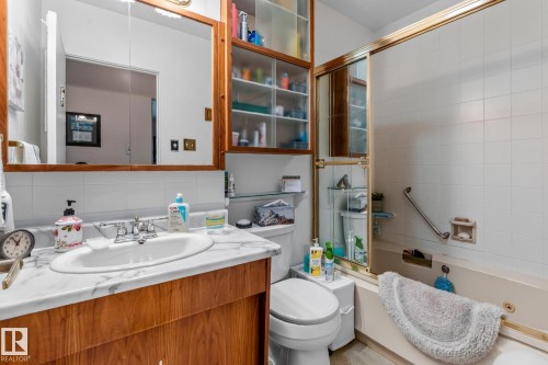 Vanity with wood-finish cabinetry, white countertop, and integrated sink - 13432 134 Street Nw, Edmonton, AB - Indoor Photo Showing Bathroom
