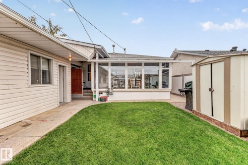 Expansive green lawn, enclosed patio structure with large windows, exterior storage shed, and a concrete pathway - 13432 134 Street Nw, Edmonton, AB - Outdoor With Deck Patio Veranda
