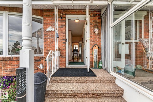 Brick exterior with bay window, white porch columns, white metal railing, and textured concrete steps - 13432 134 Street Nw, Edmonton, AB - Outdoor