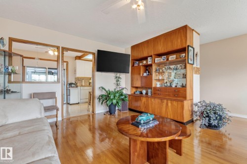 Polished wood-finish flooring throughout, integrated wood cabinetry with display cases, and a ceiling fan - 13432 134 Street Nw, Edmonton, AB - Indoor Photo Showing Living Room