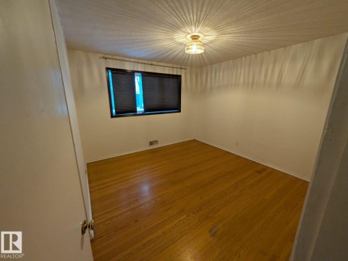 Bright, rectangular room featuring warm wood-finish flooring, white walls, and a recessed ceiling light fixture - 9733 143 Street Nw, Edmonton, AB - Indoor Photo Showing Other Room