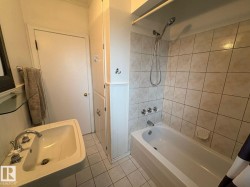Pedestal sink with chrome fixtures, built-in storage cabinetry, white subway tile tub surround, and tiled flooring - 