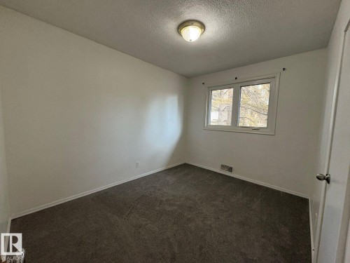 Neutral wall paint, textured ceiling, flush mount ceiling light, dual-pane window, and carpet flooring - 9733 143 Street Nw, Edmonton, AB - Indoor Photo Showing Other Room