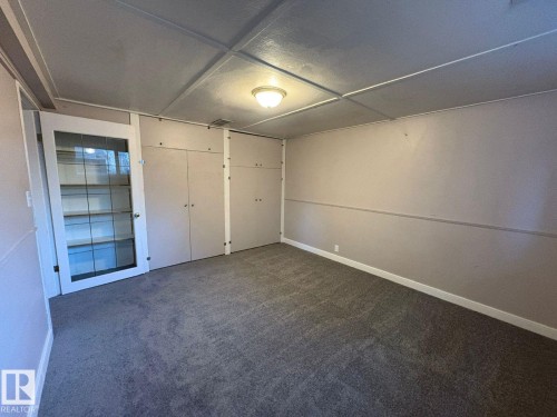 Recessed built-in cabinetry, glass-panel door, wall-to-wall carpeting, and flush mount lighting - 9733 143 Street Nw, Edmonton, AB - Indoor Photo Showing Other Room