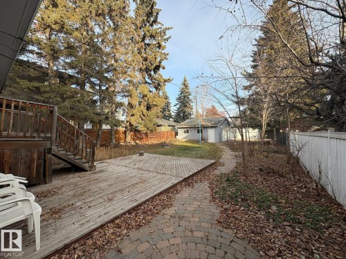 Expansive backyard featuring a multi-level wood deck, a brick paver pathway, and mature evergreen trees - 9733 143 Street Nw, Edmonton, AB - Outdoor