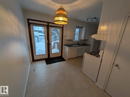 Kitchen featuring white cabinetry, a double basin sink, and a four-burner range - 9733 143 Street Nw, Edmonton, AB - Indoor