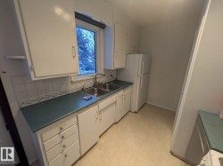 Kitchen featuring white cabinetry, dual basin stainless steel sink, and light-colored flooring - 