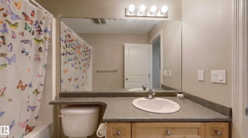 Bathroom featuring an integrated sink, wood-finish vanity, large wall mirror, and a three-light fixture - 21207 90 Ave Nw, Edmonton, AB - Indoor Photo Showing Bathroom