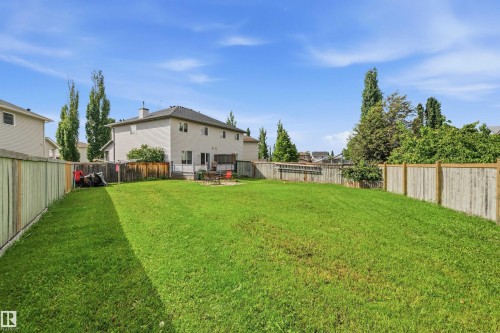 Expansive backyard featuring a manicured lawn, full perimeter fencing, a second-story deck, and mature landscaping - 21207 90 Ave Nw, Edmonton, AB - Outdoor With Backyard