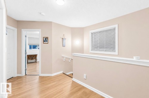 Wood-finish flooring throughout, complemented by light-toned wall paint and white trim - 21207 90 Ave Nw, Edmonton, AB - Indoor Photo Showing Other Room