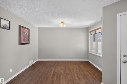 Hardwood flooring, neutral gray wall tones, ceiling-mounted light fixture, and a window with blinds - 16515 139 Street Nw, Edmonton, AB - Indoor Photo Showing Other Room
