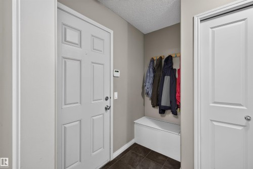 Entryway featuring a paneled door, dark tile flooring, and a built-in storage bench with wood hooks - 16515 139 Street Nw, Edmonton, AB - Indoor Photo Showing Other Room