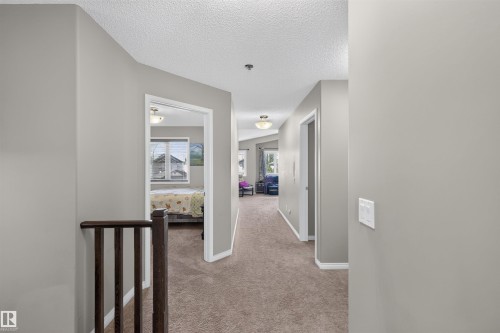 Carpeted hallway with light gray walls, white trim, and a dark wood-finish railing - 16515 139 Street Nw, Edmonton, AB - Indoor Photo Showing Other Room