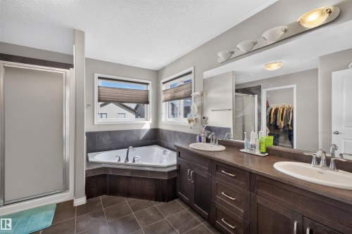 Dual vanity with dark wood-finish cabinetry, a large mirror, and individual sinks - 16515 139 Street Nw, Edmonton, AB - Indoor Photo Showing Bathroom