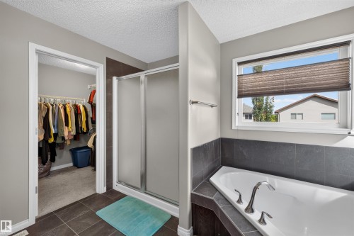 Soaking tub with deck-mounted fixtures, separate shower with frosted glass enclosure, and a walk-in closet - 16515 139 Street Nw, Edmonton, AB - Indoor Photo Showing Bathroom
