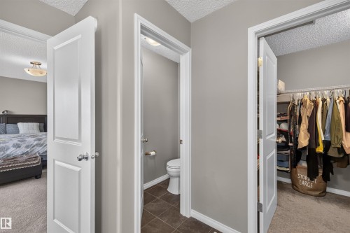 Neutral wall paint with white trim, interior doors with brushed nickel hardware, built-in closet shelving, and textured ceilings - 16515 139 Street Nw, Edmonton, AB - Indoor