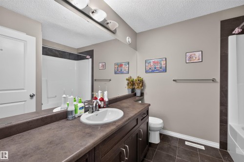 Bathroom featuring a vanity with an integrated sink, dark cabinetry, and a large mirror with overhead lighting - 16515 139 Street Nw, Edmonton, AB - Indoor Photo Showing Bathroom