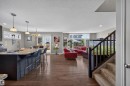 Open-concept living area with wood-finish flooring, a kitchen island with stone countertops, pendant lighting, and a sliding glass door to the exterior - 16515 139 Street Nw, Edmonton, AB  - Indoor Photo Showing Kitchen With Upgraded Kitchen 