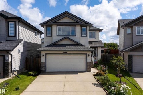 Two-story property featuring light-colored siding with dark trim accents, an attached two-car garage, and a concrete driveway - 16515 139 Street Nw, Edmonton, AB - Outdoor With Facade