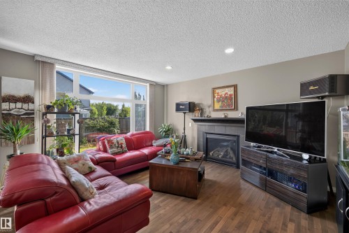 Wide picture windows, wood-finish flooring, recessed ceiling lighting, and a fireplace with a dark mantel - 16515 139 Street Nw, Edmonton, AB - Indoor Photo Showing Living Room With Fireplace