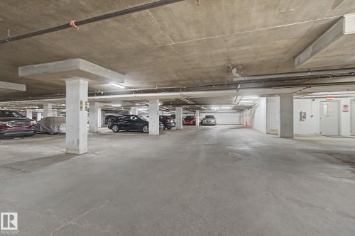 Underground parking garage with concrete flooring, concrete ceiling, and exposed utility piping - #226 17011 67 Av Nw, Edmonton, AB - Indoor Photo Showing Garage
