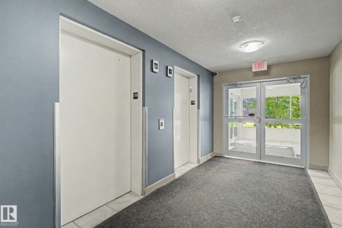 Dual elevators with brushed metal accents - #226 17011 67 Av Nw, Edmonton, AB - Indoor Photo Showing Other Room