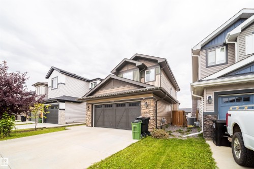 Two-story residence featuring a shingle and stone facade, an attached double garage, and a concrete driveway - 9903 222 Street Nw, Edmonton, AB 