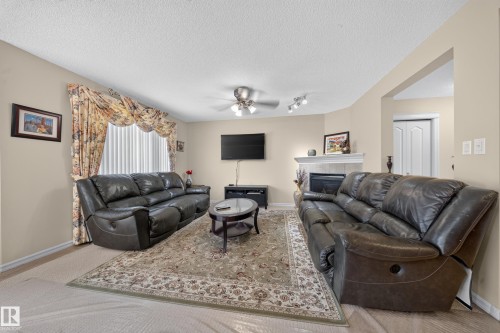 Recessed ceiling lighting, a ceiling fan, and a built-in fireplace with a tiled surround - 2518 33A Avenue Nw, Edmonton, AB - Indoor Photo Showing Living Room With Fireplace