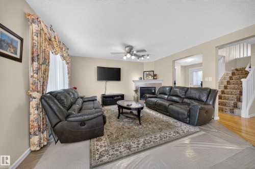 Living area featuring a ceiling fan, fireplace with mantel, and hardwood flooring - 2518 33A Avenue Nw, Edmonton, AB - Indoor Photo Showing Living Room With Fireplace