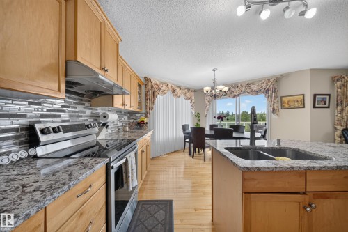 Kitchen featuring wood cabinetry, stainless steel appliances, a tile backsplash, and light-colored countertops - 2518 33A Avenue Nw, Edmonton, AB - Indoor Photo Showing Kitchen With Double Sink With Upgraded Kitchen