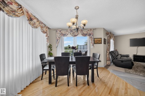 Hardwood-finish flooring, recessed ceiling, built-in chandelier, vertical blinds, and a sliding glass door - 2518 33A Avenue Nw, Edmonton, AB - Indoor Photo Showing Dining Room