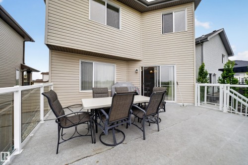 Exterior featuring tan siding, a concrete deck, glass panel railing, and a sliding glass door - 2518 33A Avenue Nw, Edmonton, AB - Outdoor With Exterior