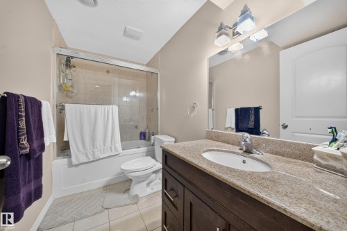 Full bathroom featuring a vanity with a stone-finish countertop, undermount sink, and a framed mirror with an overhead light fixture - 2518 33A Avenue Nw, Edmonton, AB - Indoor Photo Showing Bathroom