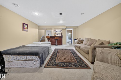 Recessed lighting illuminates a spacious room featuring carpeting, a built-in wet bar with wood-finish cabinetry, and a full bathroom - 2518 33A Avenue Nw, Edmonton, AB - Indoor