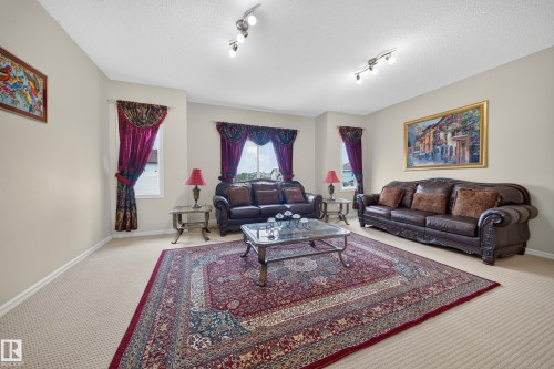 Neutral wall paint, light-colored carpeting, two windows, and track lighting - 2518 33A Avenue Nw, Edmonton, AB - Indoor Photo Showing Living Room
