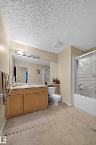 Single vanity with light wood-finish cabinetry, integrated sink, and an expansive wall mirror - 2518 33A Avenue Nw, Edmonton, AB - Indoor Photo Showing Bathroom