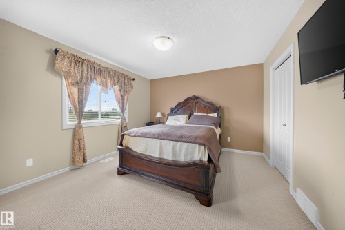Carpeted flooring with a textured pattern, a window with horizontal blinds, a white bi-fold closet door, and a built-in overhead light fixture - 2518 33A Avenue Nw, Edmonton, AB - Indoor Photo Showing Bedroom