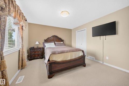 Wall-to-wall carpeting with light neutral paint, a large window, and a built-in closet with bi-fold doors - 2518 33A Avenue Nw, Edmonton, AB - Indoor Photo Showing Bedroom
