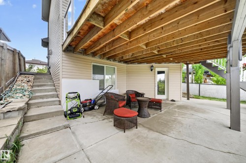 Concrete patio with overhead wood-beam deck structure and exterior lighting - 2518 33A Avenue Nw, Edmonton, AB - Outdoor With Exterior
