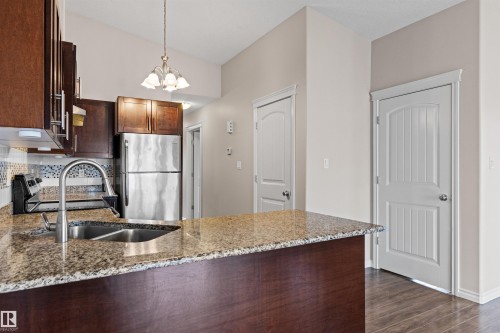 Kitchen featuring a dual-basin stainless steel sink with a high-arc faucet, granite countertops, and dark wood cabinetry - 10634 155 Street Nw, Edmonton, AB - Indoor Photo Showing Kitchen With Double Sink With Upgraded Kitchen