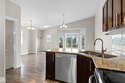 Kitchen island featuring a dual basin sink with a gooseneck faucet, stainless steel dishwasher, and dark wood-finish cabinetry - 10634 155 Street Nw, Edmonton, AB - Indoor Photo Showing Kitchen With Double Sink