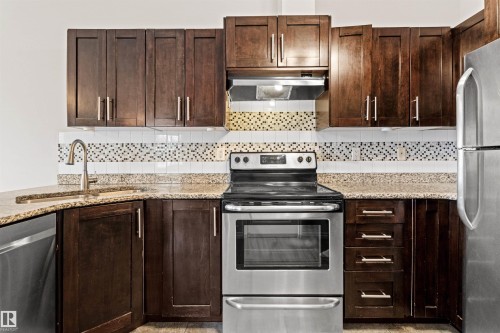 Kitchen featuring dark wood-finish cabinetry, stainless steel appliances, and a mosaic tile backsplash - 10634 155 Street Nw, Edmonton, AB - Indoor Photo Showing Kitchen