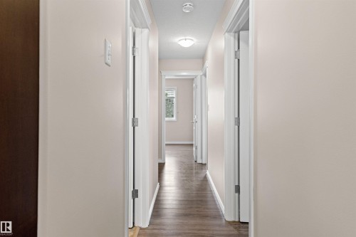 Hallway with wood-finish flooring, light neutral wall paint, white trim, and flush mount lighting - 10634 155 Street Nw, Edmonton, AB - Indoor Photo Showing Other Room