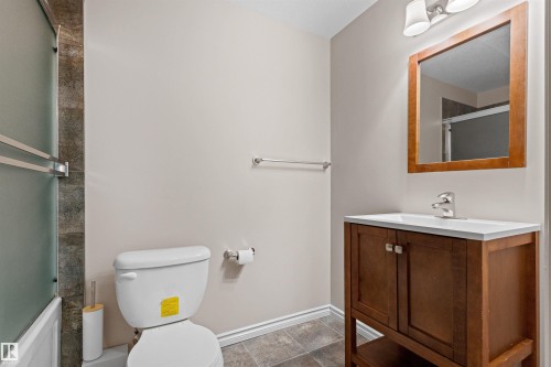 Bathroom featuring a wood-finish vanity with an integrated sink, a framed mirror, and a two-light fixture - 10634 155 Street Nw, Edmonton, AB - Indoor Photo Showing Bathroom