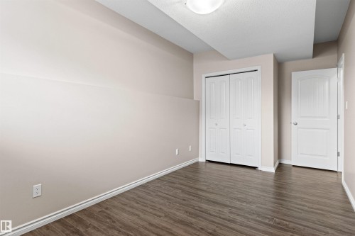 Interior room featuring wood-finish flooring, light neutral-toned walls, white baseboards, and a white ceiling with a flush-mount light fixture - 10634 155 Street Nw, Edmonton, AB - Indoor Photo Showing Other Room