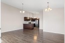 Open-concept living space featuring wood-finish flooring, a kitchen island with stone countertop, dark wood cabinetry, stainless steel appliances, and a mosaic tile backsplash - 10634 155 Street Nw, Edmonton, AB  - Indoor Photo Showing Kitchen 