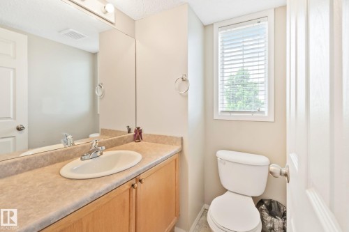 Bathroom vanity with a laminate countertop, integrated sink, and light wood-finish cabinetry - 3769 21 Street Nw, Edmonton, AB - Indoor Photo Showing Bathroom