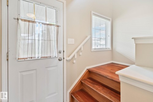 Entryway featuring a white paneled door with an upper window, wood-finish stairs, and a white handrail - 3769 21 Street Nw, Edmonton, AB - Indoor Photo Showing Other Room